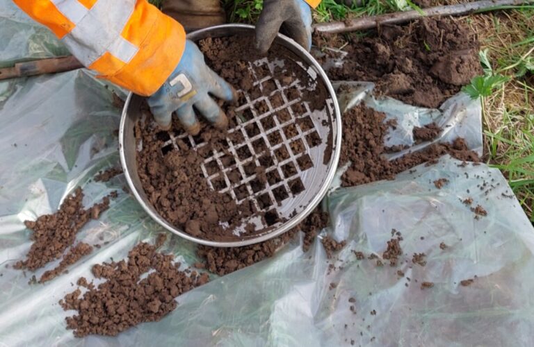 Veldwerker zeeft de grond voor asbestonderzoek